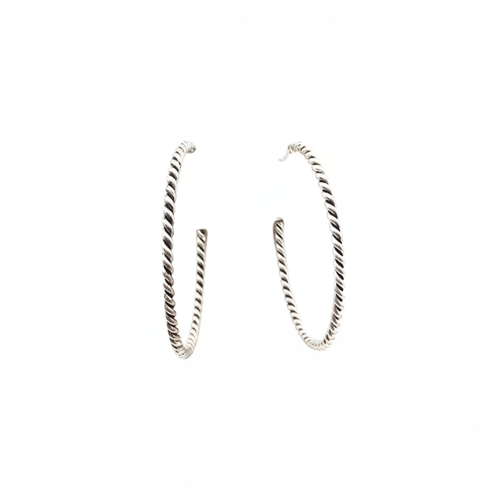 Pair of silver hoop earrings on a light pink cushion
