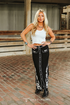 Woman wearing a white top and black pants with animal print details on a brick pavement.