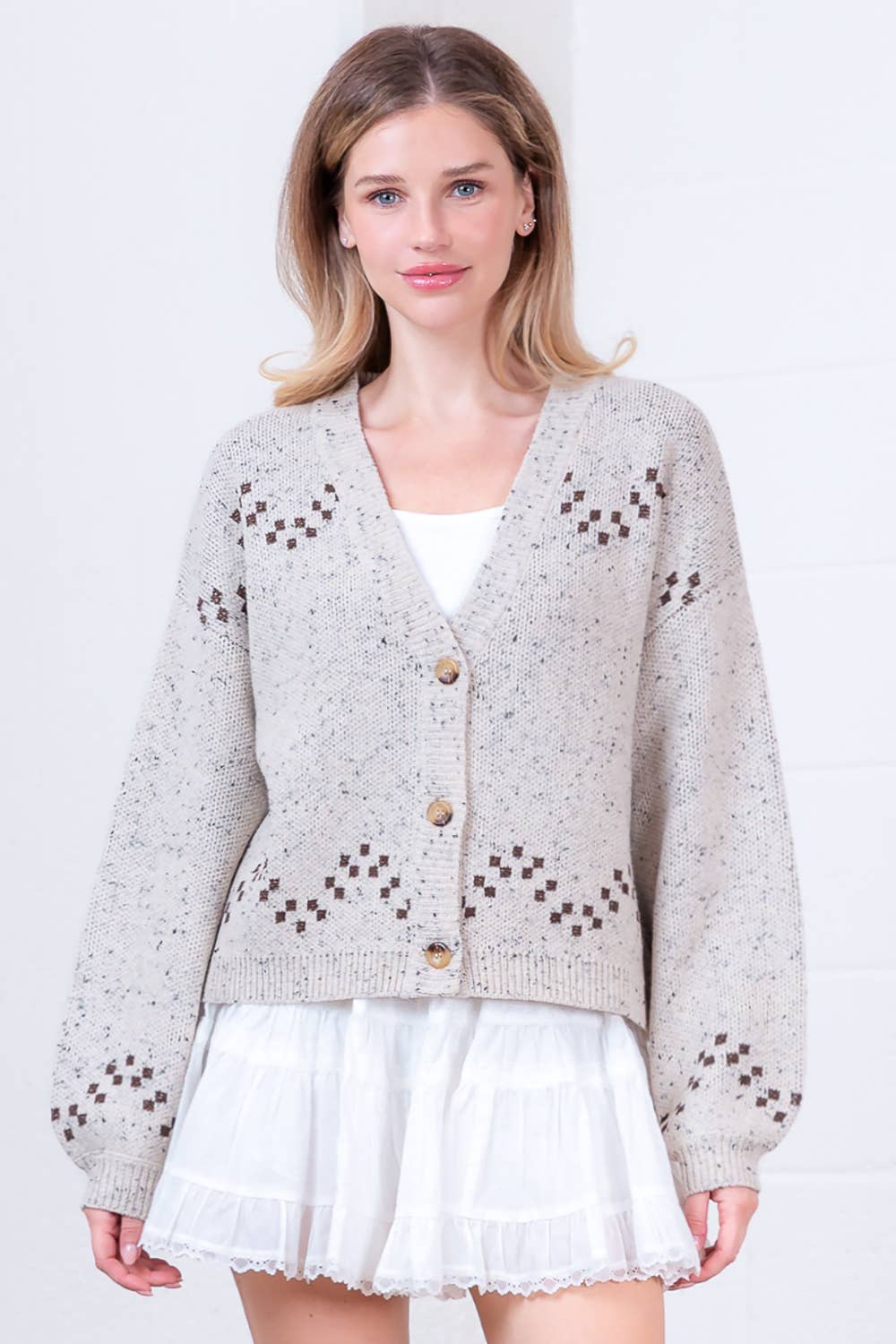 Woman wearing a light gray cardigan with decorative buttons on a white background