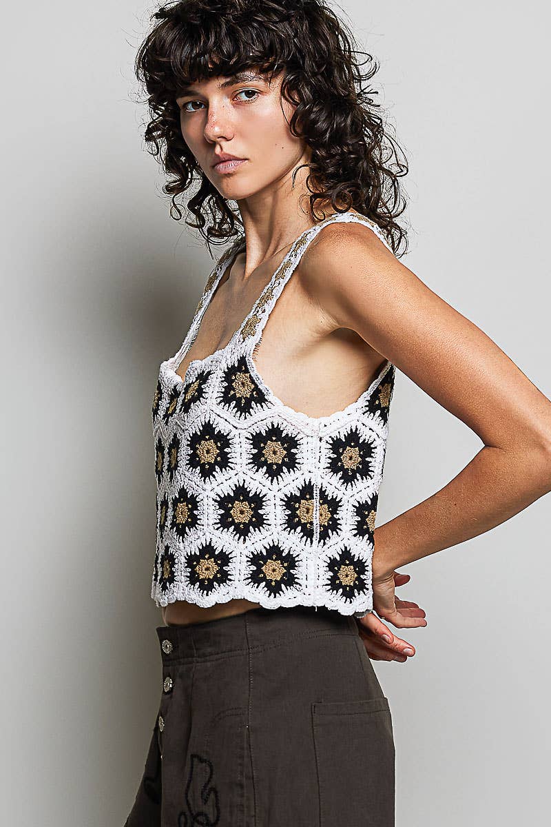 Model wearing the High Desert Crochet Tank, a handcrafted crochet crop top featuring a square neckline, wide floral-weave straps, scalloped edges, and a black, ivory, and camel granny square pattern, paired with an embroidered brown skirt.