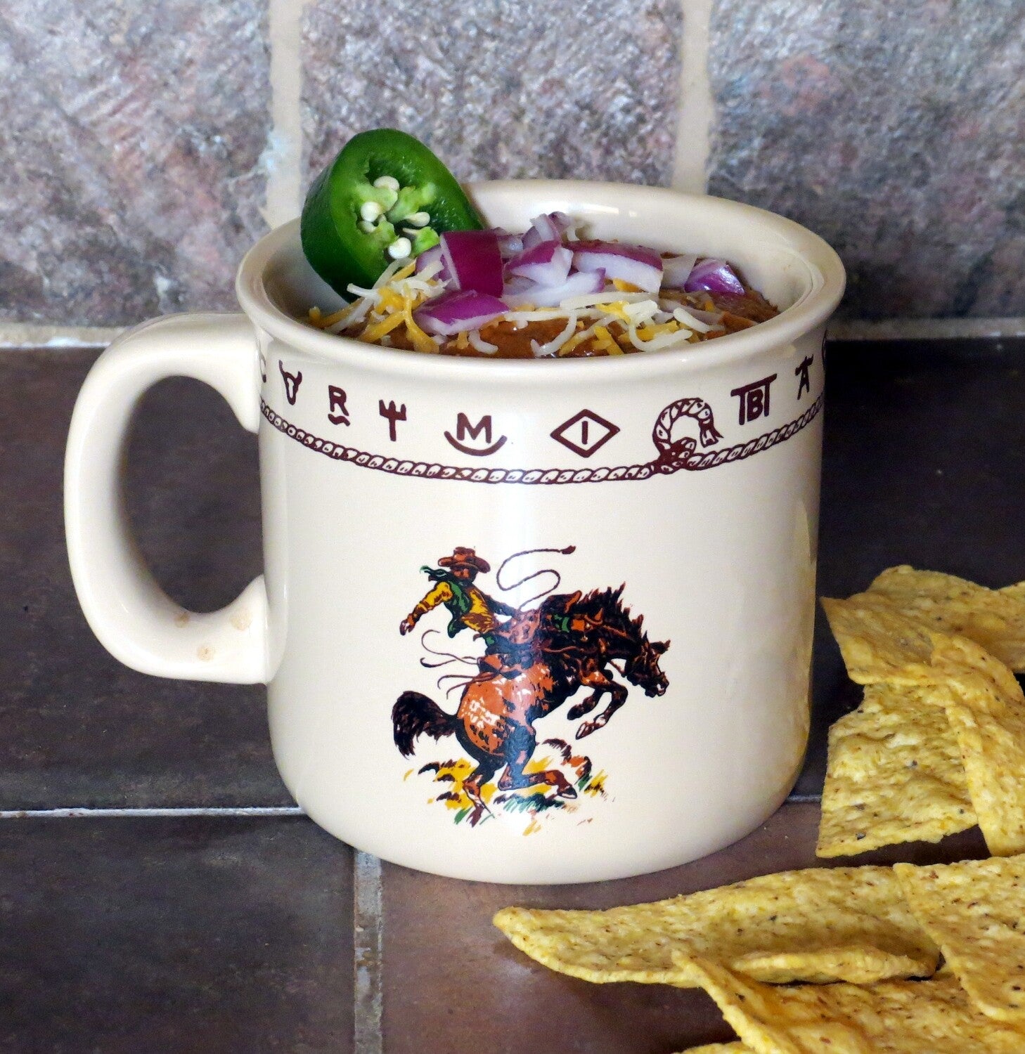 Ivory ceramic western mug featuring a bronco buster illustration with dark brown rope and brand details. Microwave and dishwasher safe, ideal for coffee, chili, cereal, or ice cream.
