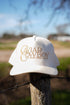 A cream-colored trucker hat with gold embroidered "Caviar Cowboy" lettering and "You Have Good Taste" slogan. A stylish blend of Western and luxury aesthetics.
