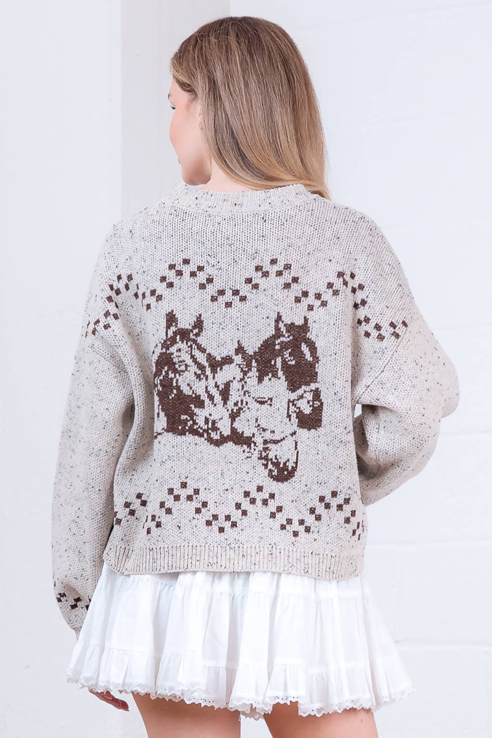 Woman wearing a beige sweater with horse design on a white background