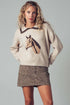 Woman wearing a sweater with a horse design and a leopard print skirt on a gray background