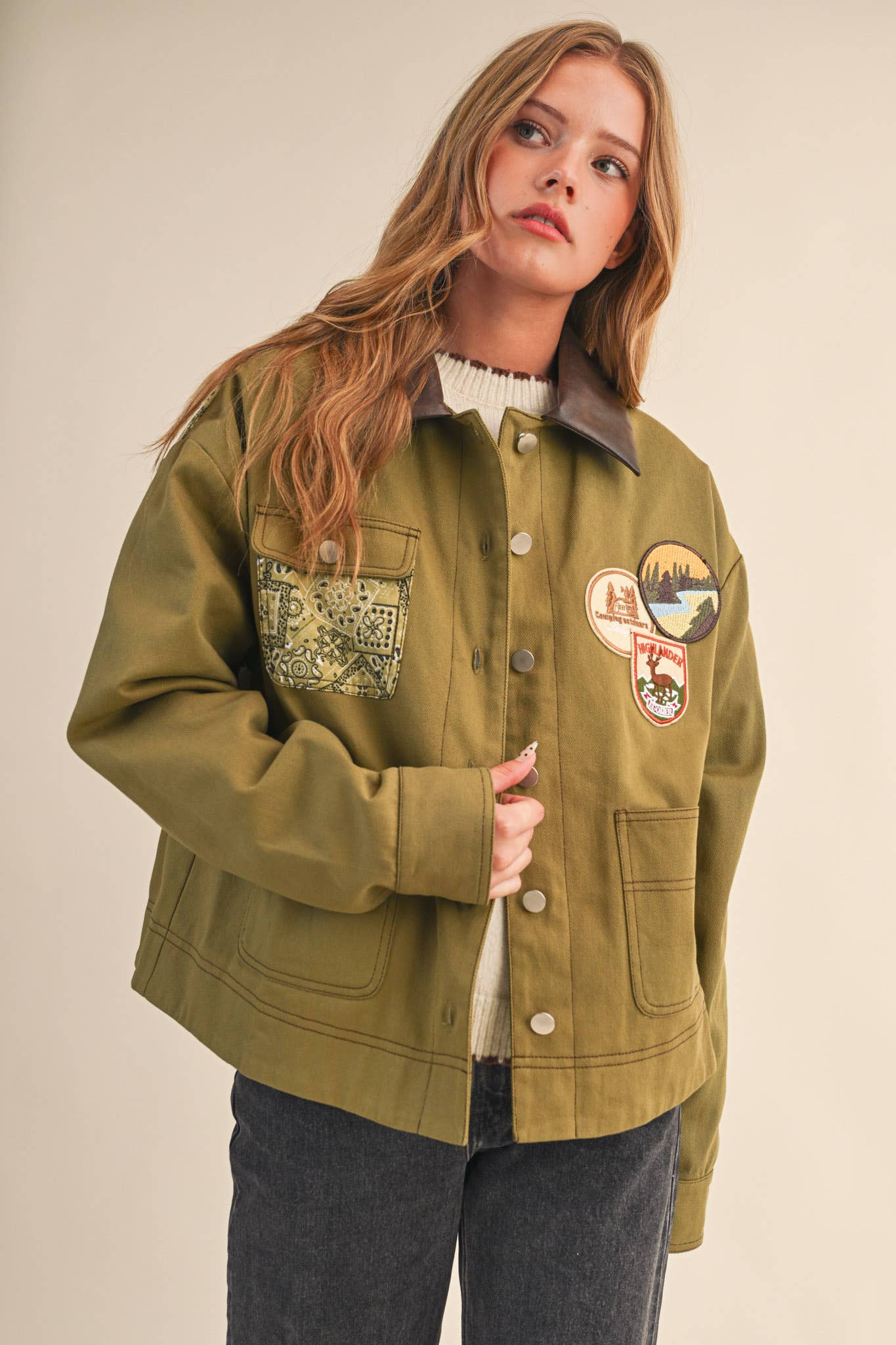Woman wearing a green jacket with patches on a beige background