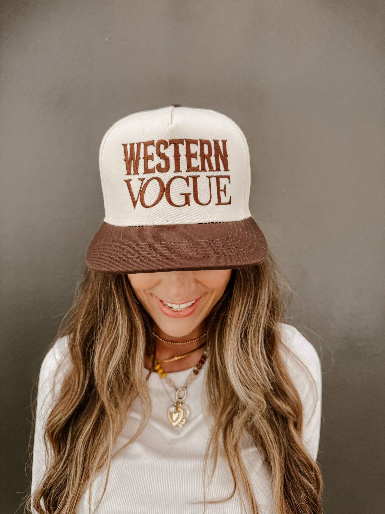 A cream and brown trucker-style hat with "WESTERN VOGUE" embroidered in bold brown lettering. A stylish fusion of Western heritage and modern fashion.