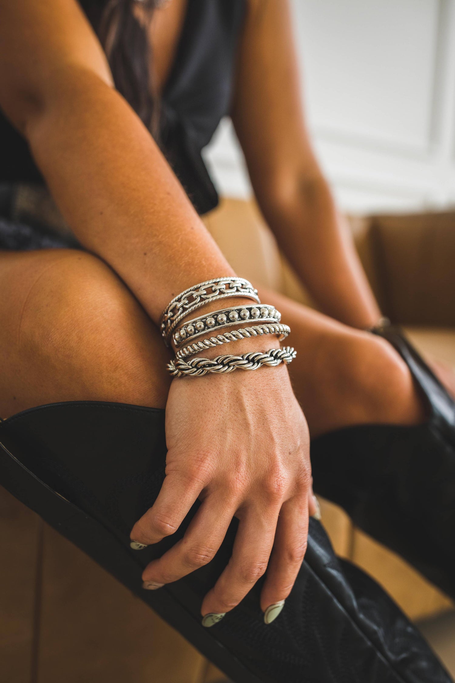 Close-up of a hand wearing multiple silver bracelets on a blurred background