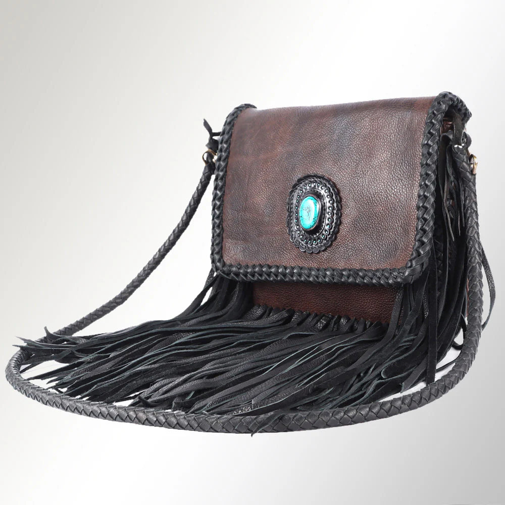 Brown leather handbag with fringe and a decorative emblem on a light gray background