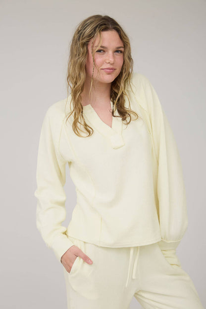 Woman wearing a light yellow outfit against a plain background