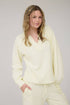 Woman wearing a light yellow outfit against a plain background