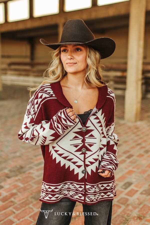 Woman wearing a patterned cardigan and cowboy hat in an indoor setting
