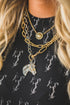 Close-up of a person wearing multiple gold necklaces with horse pendants on a black background.