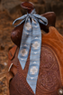 Blue patterned ribbon tied on a brown leather saddle