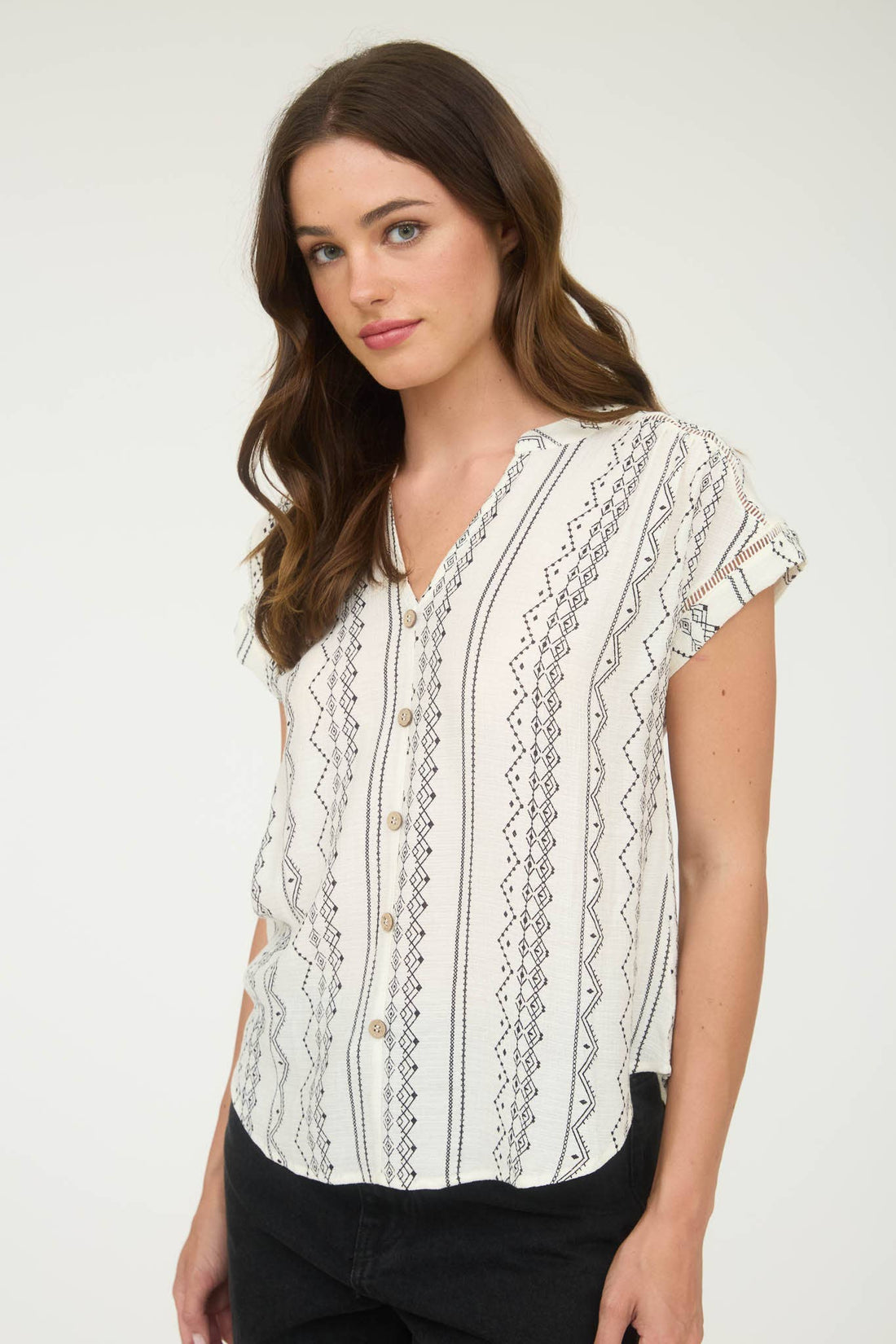 Woman wearing a white blouse with black patterns on a white background
