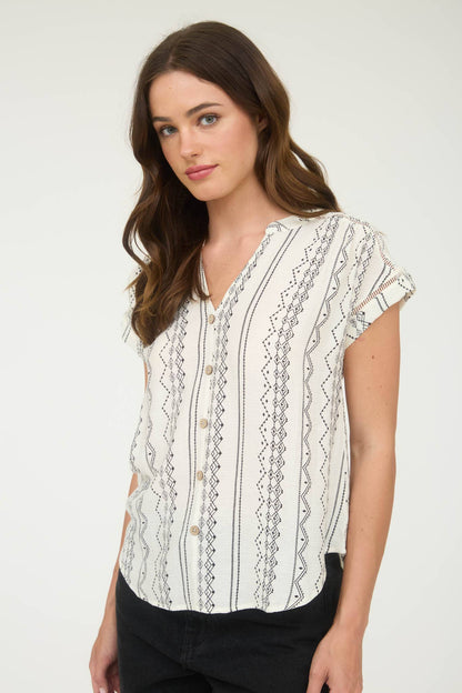 Woman wearing a white blouse with black patterns on a white background