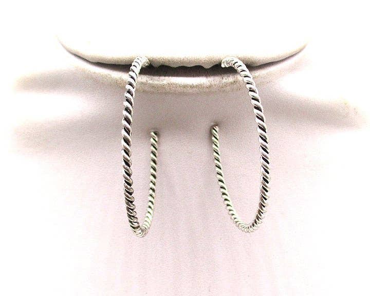 Pair of silver hoop earrings on a light pink cushion
