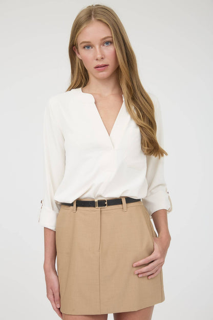 Woman wearing a white blouse and beige skirt on a plain background