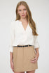 Woman wearing a white blouse and beige skirt on a plain background