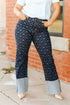 Person wearing navy patterned pants with gray cuffs standing against a brick wall.