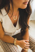 Woman wearing gold jewelry including a necklace, bracelet, and ring.