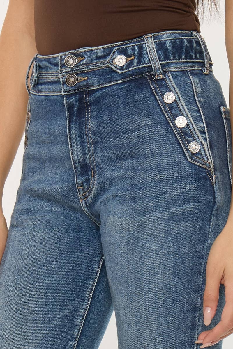 Close-up of blue jeans with button details on a plain background