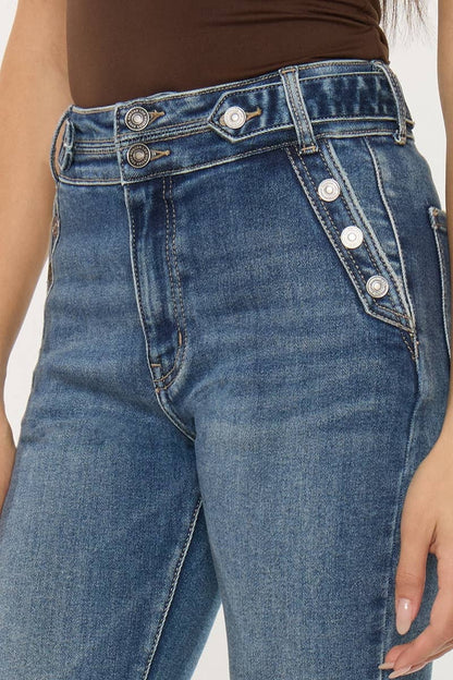 Close-up of blue jeans with button details on a plain background