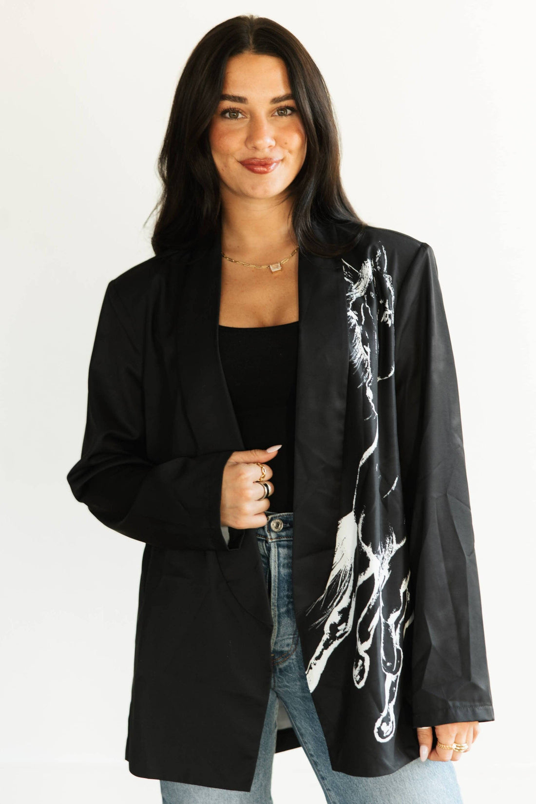 Woman wearing a black blazer with white abstract design on a plain background