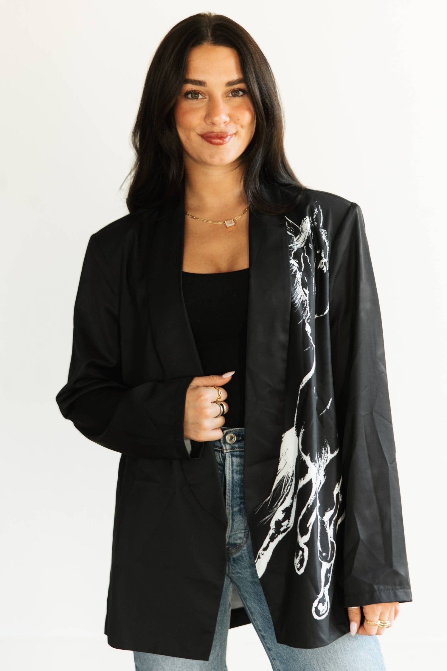 Woman wearing a black blazer with white abstract design on a plain background