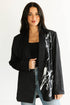 Woman wearing a black blazer with white abstract design on a plain background
