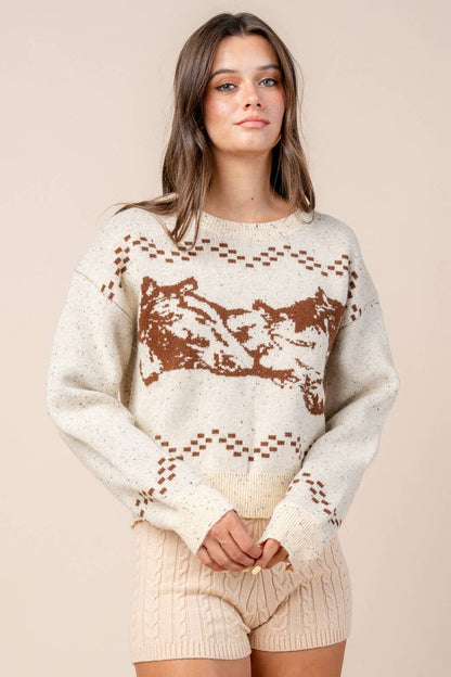 Woman wearing a cream sweater with brown pattern on a beige background