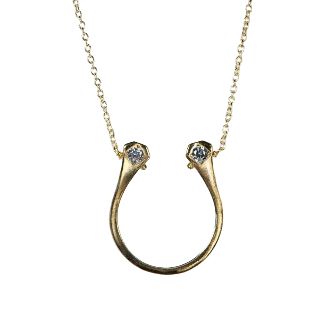 Gold necklace with a horseshoe-shaped pendant on a light gray background