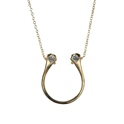 Gold necklace with a horseshoe-shaped pendant on a light gray background