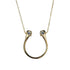 Gold necklace with a horseshoe-shaped pendant on a light gray background