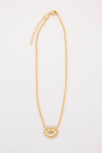 Gold necklace with a circular pendant on a light gray background