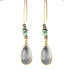 Teardrop-shaped earrings with gold and turquoise accents on a dark background