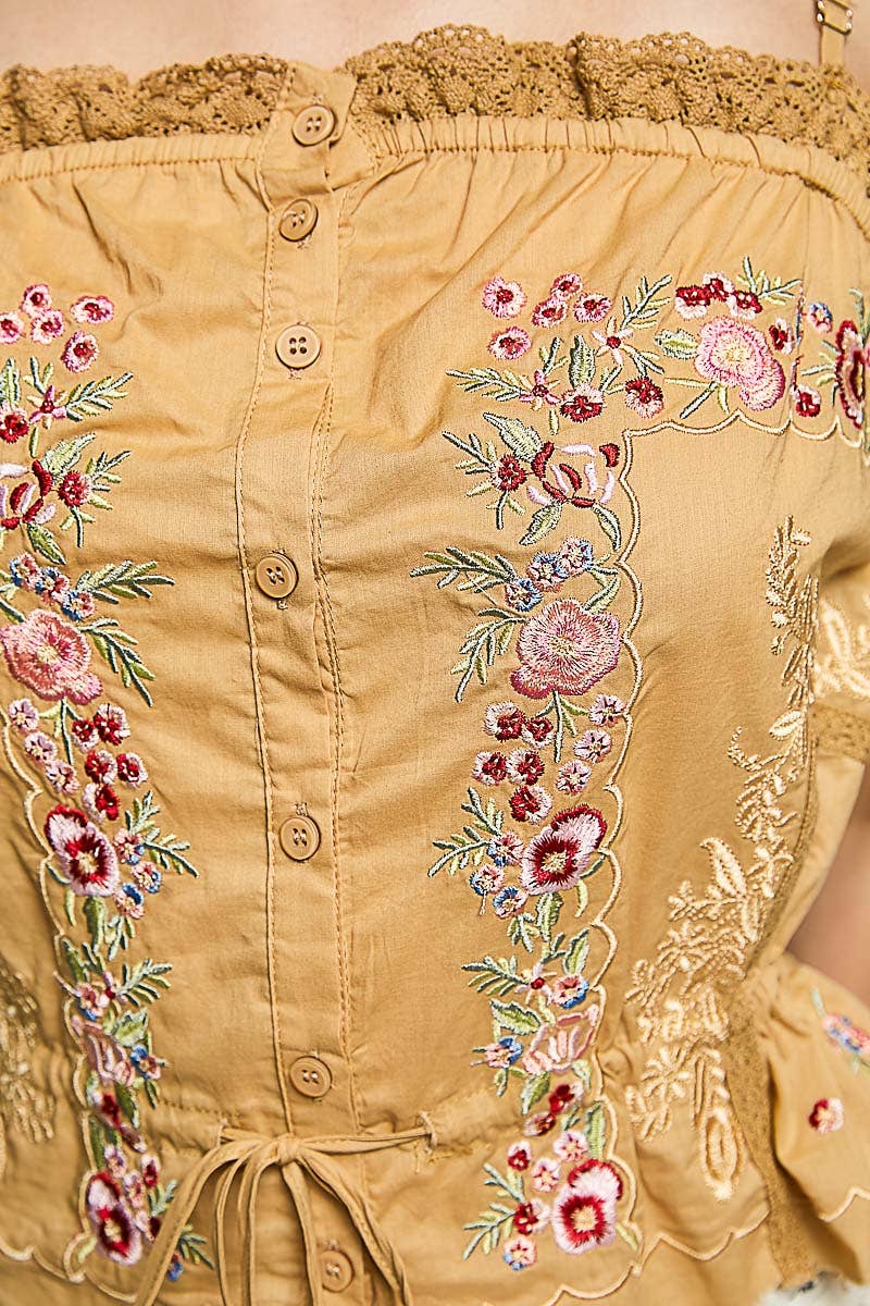 Model wearing the Golden Mesa Tank, a golden tan sleeveless poplin top featuring floral embroidery, decorative trim, button-front closure, adjustable front tie, and a softly gathered waist, paired with a cream floral skirt.
