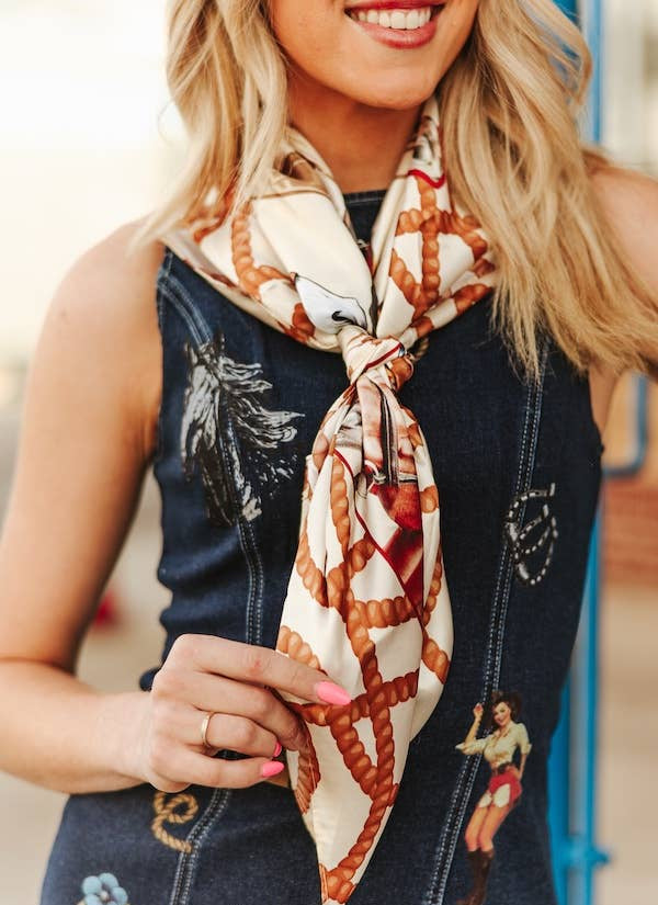 Woman wearing a patterned scarf with a denim vest featuring embroidered designs.
