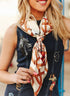 Woman wearing a patterned scarf with a denim vest featuring embroidered designs.