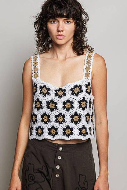 Model wearing the High Desert Crochet Tank, a handcrafted crochet crop top featuring a square neckline, wide floral-weave straps, scalloped edges, and a black, ivory, and camel granny square pattern, paired with an embroidered brown skirt.