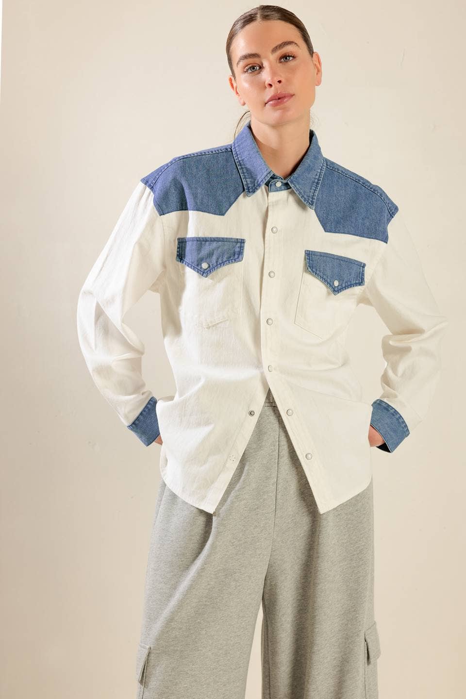Woman wearing an ivory western button-up shirt with contrast denim yoke and chest pockets, styled with gray wide-leg pants.