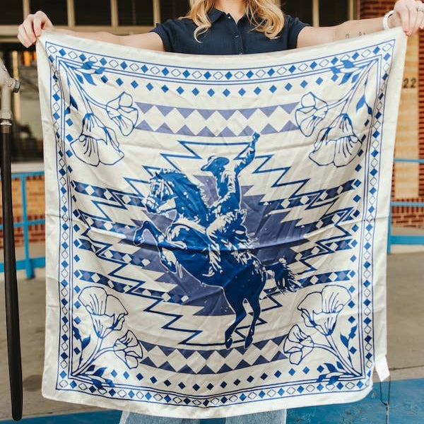 Woman holding a large blue and white patterned scarf with &