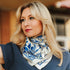Woman wearing a blue and white patterned scarf, standing outdoors.