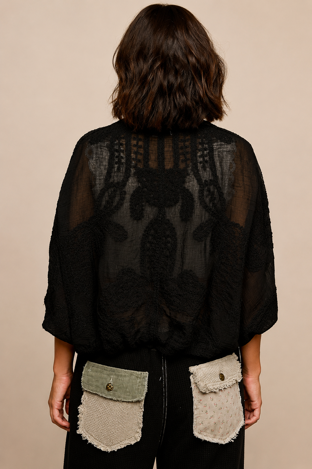 Model wearing the Noir Canyon Kimono, a lightweight black open-front cardigan featuring a textured crochet-inspired design, relaxed fit, and three-quarter sleeves, layered over a cream lace-trim camisole and patchwork lounge pants.