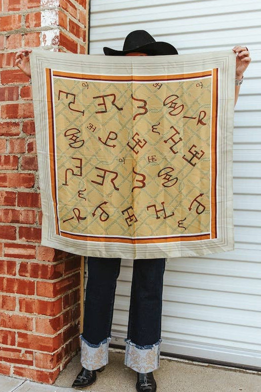 Person holding a large quilt with intricate patterns against a brick wall.