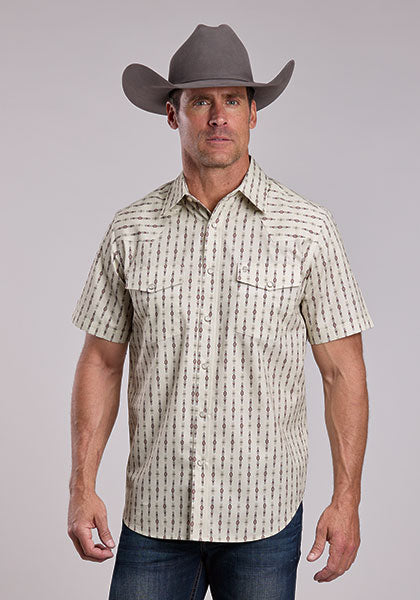 Man wearing a patterned short-sleeve shirt and cowboy hat against a gray background