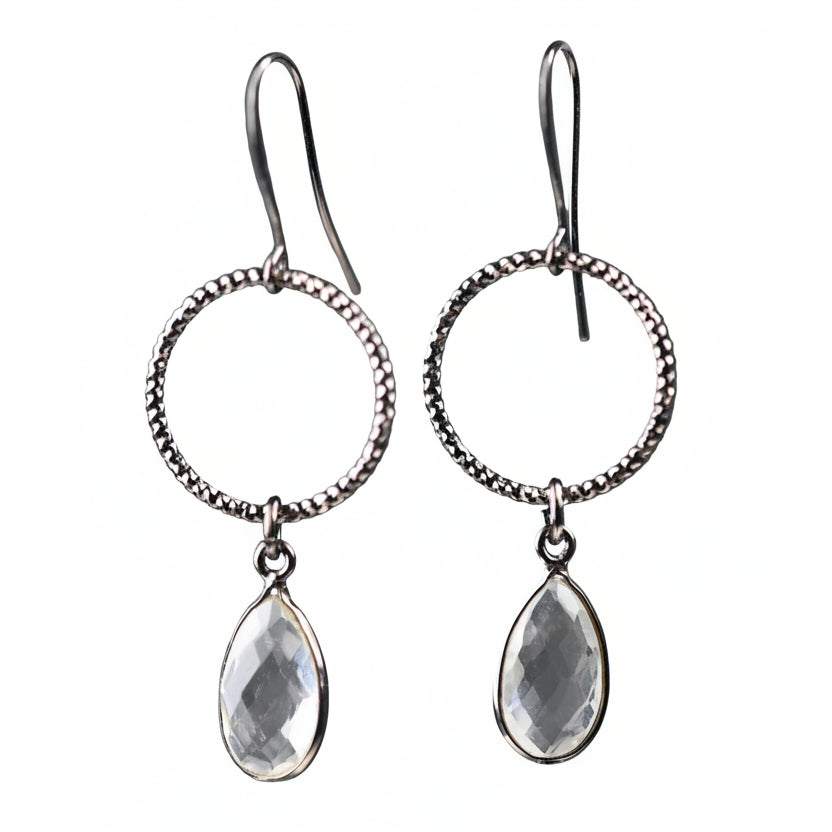 Silver hoop earrings with teardrop-shaped clear stones on a white background