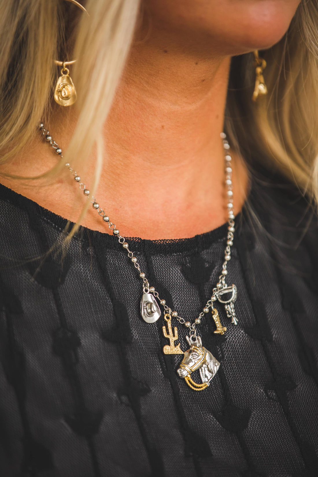 Close-up of a necklace with various charms worn by a person against a black background