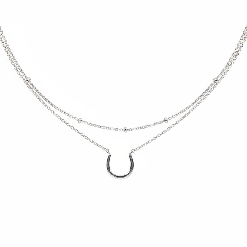 Necklace with horseshoe charm on a card with text and brand logo.