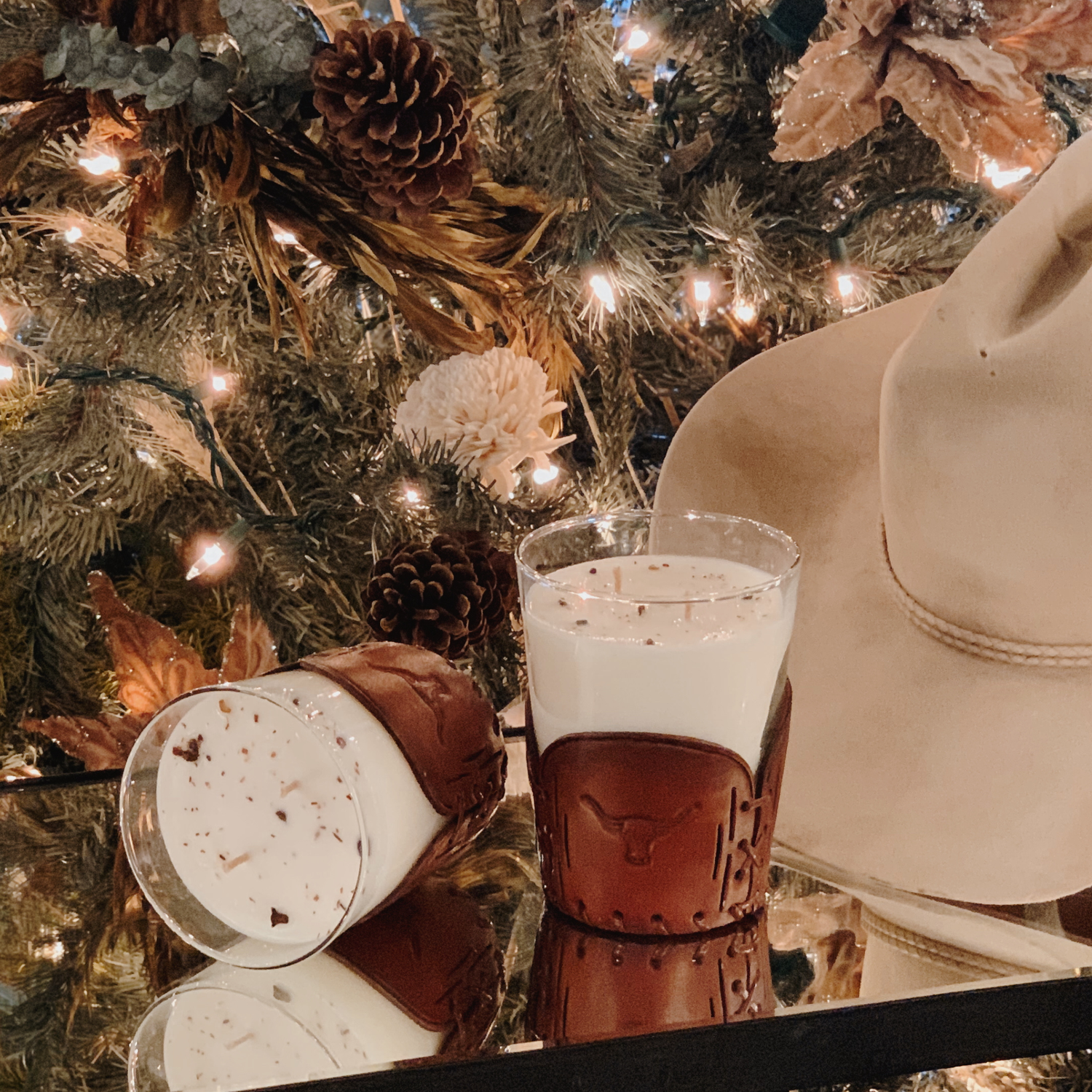 Glass of hot chocolate with whipped cream next to a Christmas tree