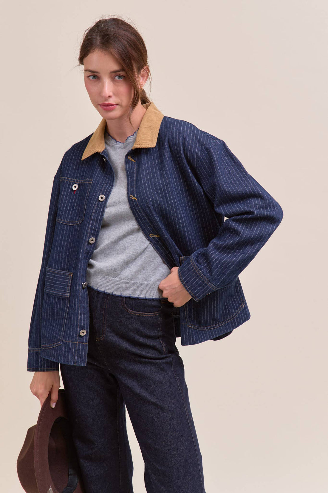 Woman wearing a blue corduroy jacket with a beige collar on a beige background